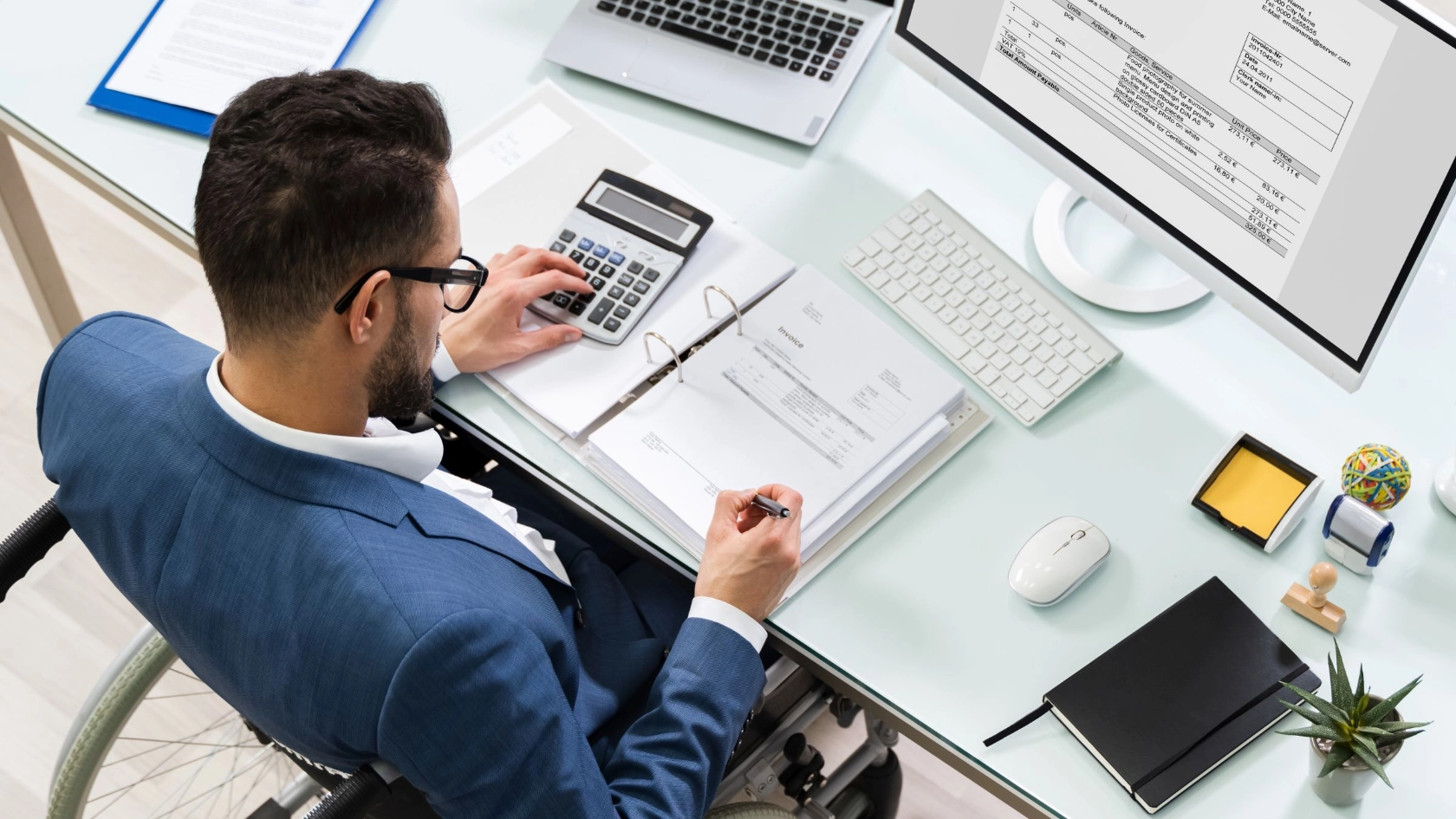 Mann im Rollstuhl arbeitet am Schreibtisch